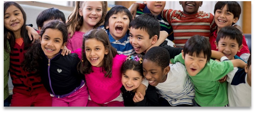 Photo of many children smiling and facing the camera with arms around each other